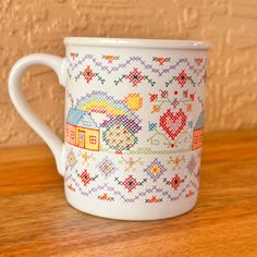 a white coffee cup with colorful designs on the outside and inside is sitting on a wooden table