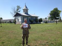 a soldier holding up a sign in front of a small church with a steeple