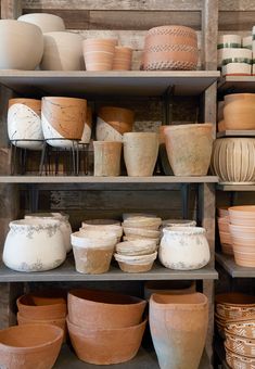 many clay pots and bowls are on shelves