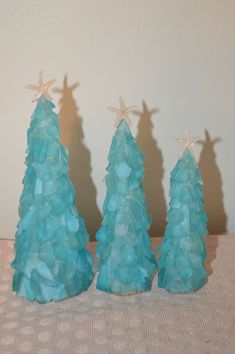 three small blue trees sitting next to each other on top of a table with starfish decorations