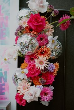 flowers and disco balls hanging from the side of a door