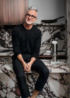 an older man sitting on top of a marble counter