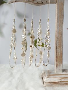 several necklaces hanging from a wooden frame on a white furnishing area with a plant in the background