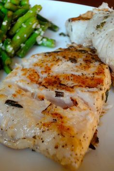 a white plate topped with fish and asparagus