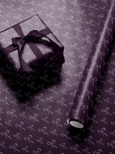 a present wrapped in purple ribbon next to a roll of wrapping paper