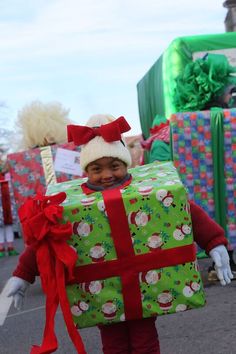 a small child is holding a large present