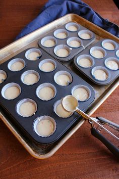 cupcake batter being poured into a muffin tin on top of a wooden table