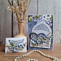 a vase with some flowers next to a card on a table and a bead necklace