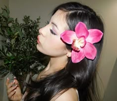 a woman with long black hair and a pink flower in her hair