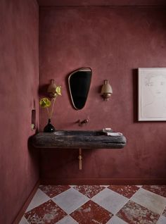 a bathroom with red walls and flooring has a sink, mirror and lamp on the wall