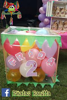 a birthday party with balloons and decorations on the grass in front of a bookcase