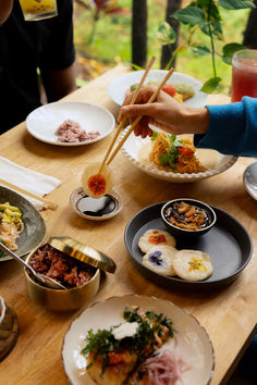 people are eating food at a table with chopsticks in their hands and bowls on the table