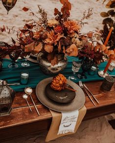 a table set up with plates and place settings for an outdoor dinner on the beach