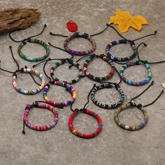 a bunch of bracelets sitting on the ground next to some leaves and a piece of wood