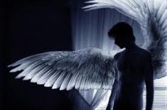 a man standing in front of a window with an angel wing on it's back