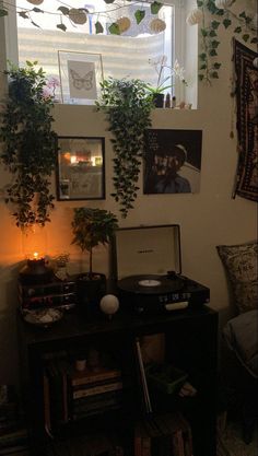 a room with plants and pictures hanging on the wall, including an old record player