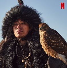 a man with an eagle on his arm in front of a blue sky and some clouds