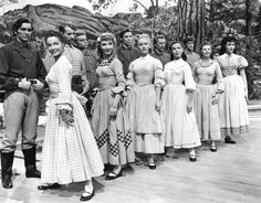 a group of people standing next to each other on a wooden floor in front of trees