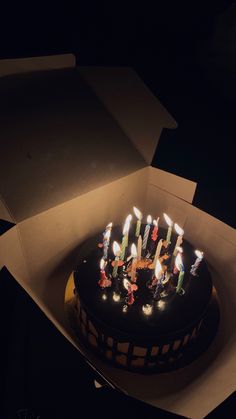 a birthday cake with lit candles in a box