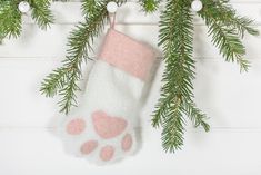 a stocking hanging from a christmas tree with pink and white paw prints on it