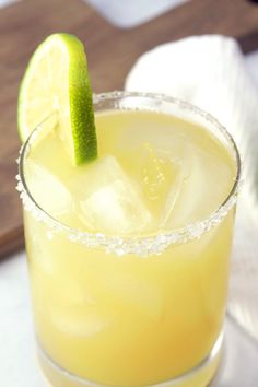 a close up of a drink in a glass with a lime slice on the rim