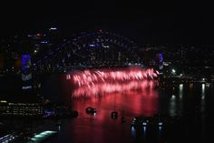 fireworks are lit up in the night sky over water and city lights, as seen from sydney harbour