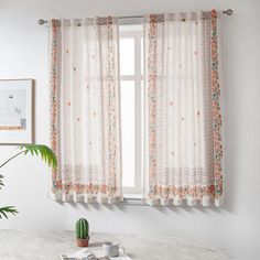 a table with a potted plant on top of it next to a window curtain