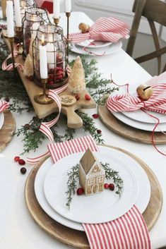 a table set for christmas with plates, napkins and candles on top of it