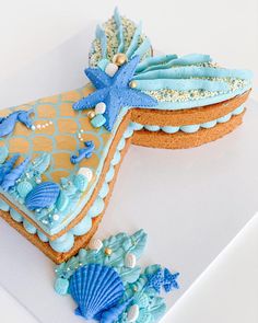 a decorated cookie with blue icing and seashells is on a white surface