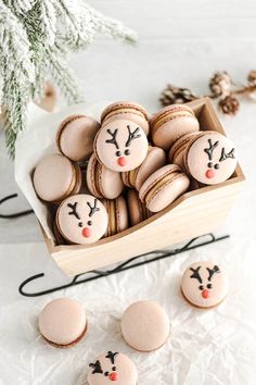 christmas cookies decorated with reindeer faces are in a wooden box next to some pine cones