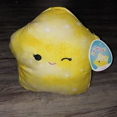 a yellow stuffed toy on a wooden floor with a tag in it's ear