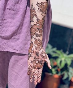 a woman's hand with henna on it and flowers painted on the arm