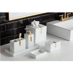 bathroom accessories including soap dispenser, toothbrush holder and tissue box in white with gold accents