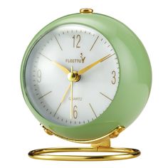 a green and white alarm clock sitting on top of a gold stand with two hands