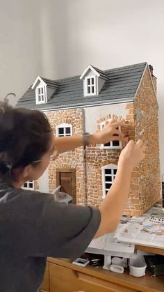 a woman is playing with a model house