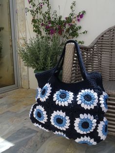 a crocheted purse sitting on top of a wooden bench next to a potted plant