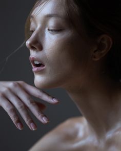 a woman with her eyes closed and hands on her chest, looking to the side