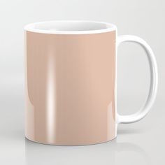 a coffee mug is shown on a white surface with light pink hues in the background