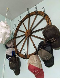 several hats are hanging on the wall next to a wagon wheel and baseball cap rack