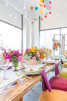 the table is set with colorful flowers and plates