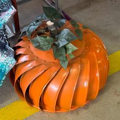 an orange pumpkin shaped planter sitting on the ground