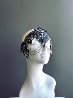 a white mannequin head with black lace and beads on it's face