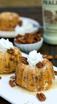 two bundt cakes on a plate with whipped cream and pecans around the edges