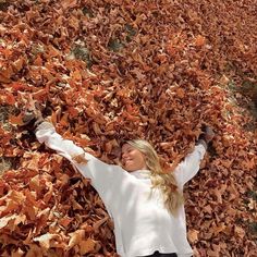 a woman laying on top of a pile of leaves