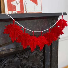 a red knitted leaf garland hanging from a fireplace mantel