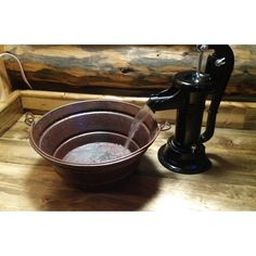 a metal bowl sitting on top of a wooden table next to a faucet