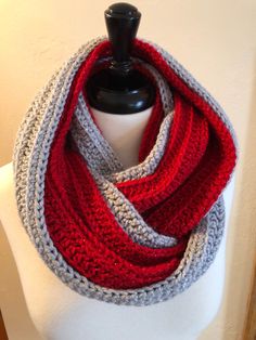 a red, grey and white crocheted scarf on a mannequin