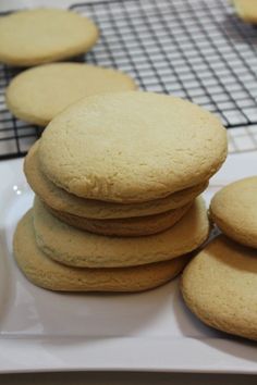 several cookies stacked on top of each other in front of a cooling rack with more cookies behind them