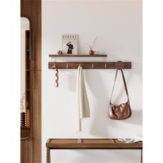 a wooden shelf holding two purses and a handbag on it's hooks