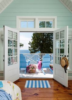 an open door leading into a bedroom with blue chairs and flowers on the bed area